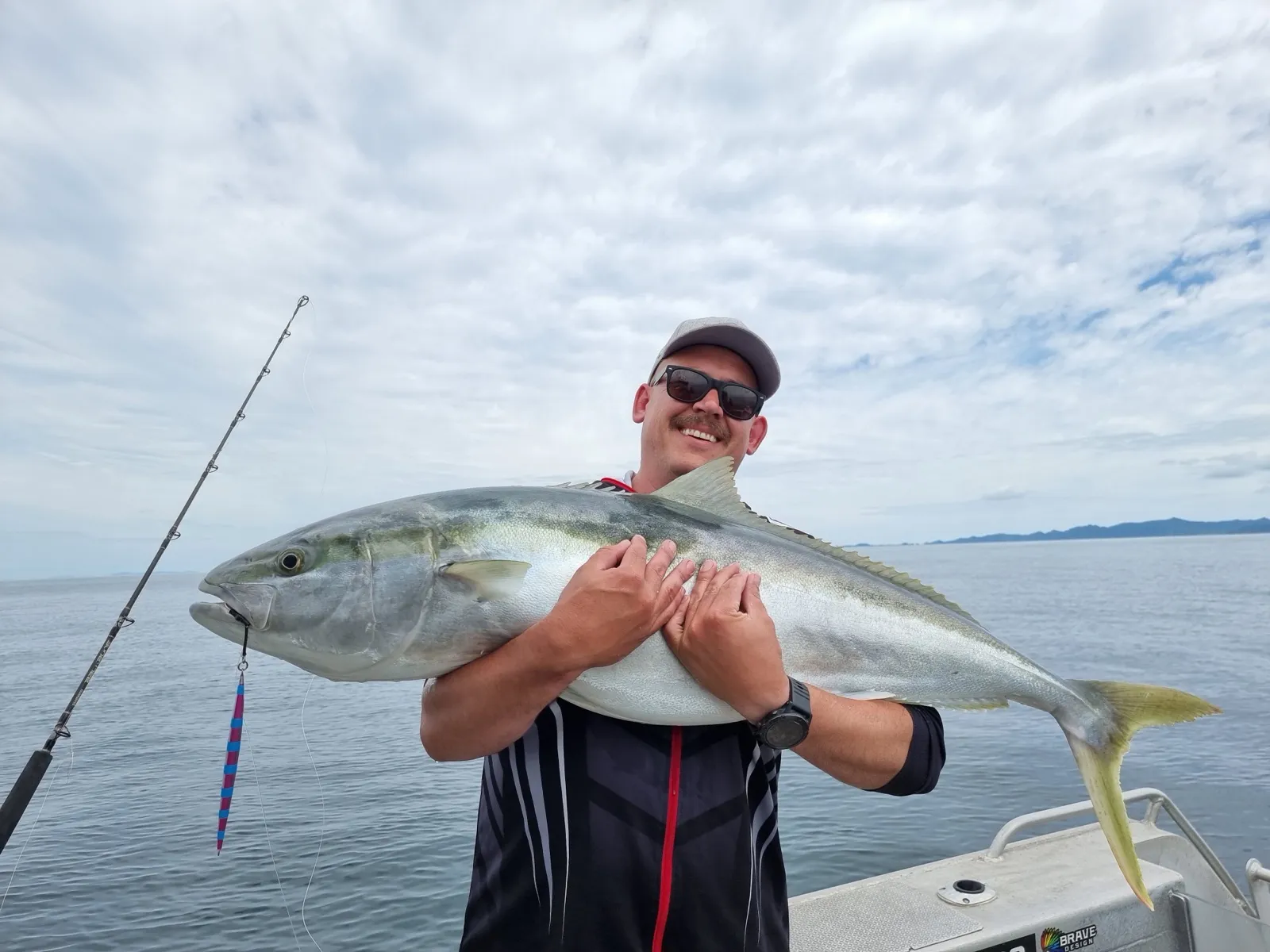 An angler holding a kingfish aboard a Fish 'N Dips charter